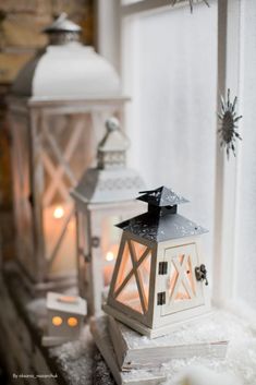 two white lanterns sitting next to each other on top of snow covered windowsills