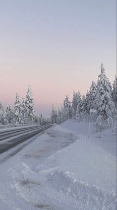 the road is covered in snow and ice as it passes by some trees on either side