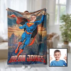 a young boy is holding up a blanket with the image of superman on it and smiling at the camera