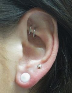 a woman with two piercings on her ear and one behind the ear is a small white ball