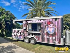 a food truck is parked on the side of the road near some trees and palm trees