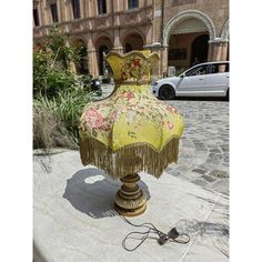 a lamp that is on top of a cement slab in front of a building with a car parked next to it