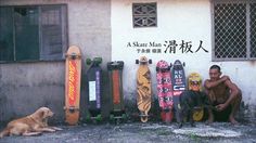 a man sitting next to skateboards and a dog