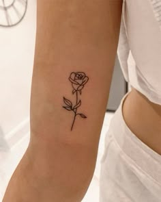 a woman's arm with a single rose tattoo on the left side of her arm