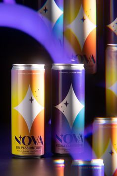 two cans of soda sitting next to each other on top of a wooden table in front of colorful lights