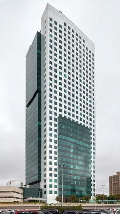 a very tall building sitting next to a parking lot filled with lots of parked cars