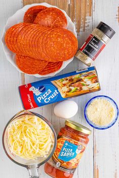 the ingredients to make this pasta dish are displayed on a white wooden surface, including eggs, cheese and tomato sauce