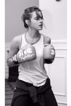 a black and white photo of a woman wearing boxing gloves with one hand on her hip