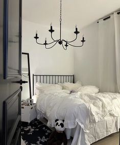 a black and white bedroom with a chandelier hanging from the ceiling, an unmade bed in front of a window