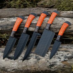 four knives with orange handles are sitting on a piece of wood