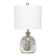 a glass table lamp with a white shade on the base and a silver finish to it