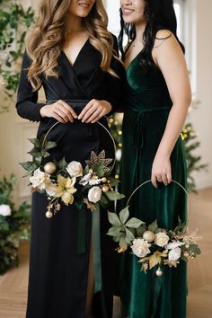 two beautiful women standing next to each other holding flowers and wreaths in their hands