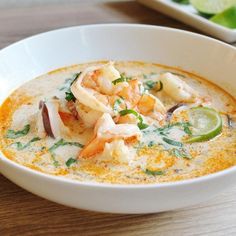 a white bowl filled with soup and garnished with shrimp