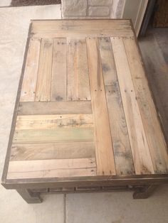 a coffee table made out of pallet wood sitting on top of a tile floor