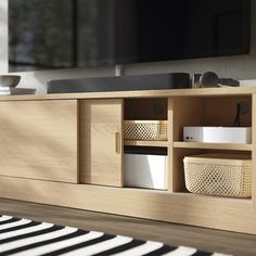 an entertainment center with drawers and baskets in front of a flat screen tv