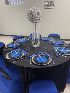 a black table with blue chairs and plates