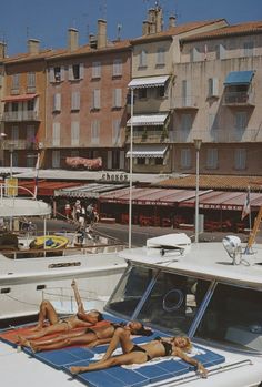 two women lounging on the back of a boat in front of several other boats