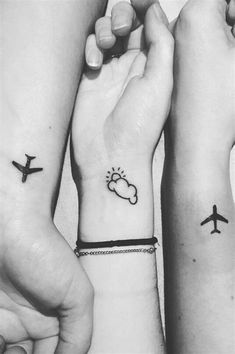 two people holding hands with small tattoos on their wrist and an airplane flying above them