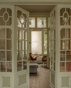 an open door leading to a living room with a couch in the corner and windows