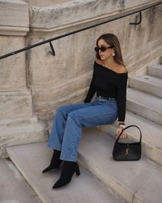 This look combines timeless elegance with a touch of modern sophistication. The off-shoulder black top perfectly highlights the collarbone, paired with high-waisted blue jeans for a casual yet chic ensemble. The black pointed-toe ankle boots add a sleek, stylish touch, while the black handbag and oversized sunglasses complete the look, making it perfect for a casual day out or a relaxed evening event.   Photo credit by: @lesperlesdebrunette Grey Outfits, Cocktail Casual Attire, Black Top Outfit, Minimalist Chic Fashion, Off The Shoulder Top Outfit, Arabian Fashion, Casual Elegant Style, Chic Clothing Style, Boots Outfit Ankle