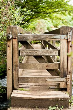 an old wooden gate that says please south's gate on the side of a river