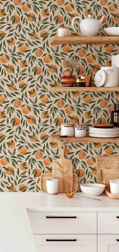 an orange wallpaper in a kitchen with white cupboards and shelves filled with dishes