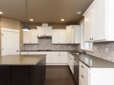 an empty kitchen with white cabinets and black counter tops