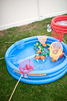 an inflatable swimming pool with toys on the grass next to two red and orange floats