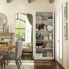 a dining room table and chairs in front of a white bookcase with open doors