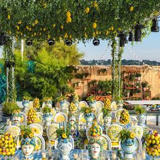 a table covered in vases filled with yellow and blue flowers next to an arbor