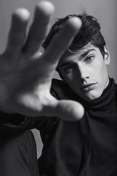 black and white photograph of a young man holding his hand up to the camera with both hands