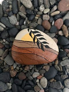 a rock sitting on top of a pile of rocks covered in gravel and stones with leaves painted on it