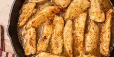 some chicken is cooking in a skillet on the table with a red and white towel