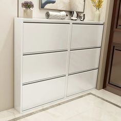 a white dresser sitting next to a painting on the wall