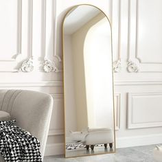 a large mirror sitting on top of a floor next to a white chair in a room