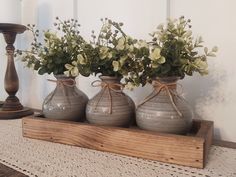 three vases with flowers are sitting on a shelf in front of a candle holder