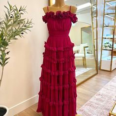 a dress on display in front of a mirror with a potted plant next to it