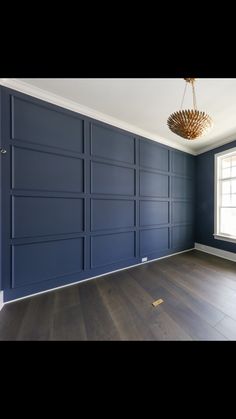 an empty room with blue walls and wood floors