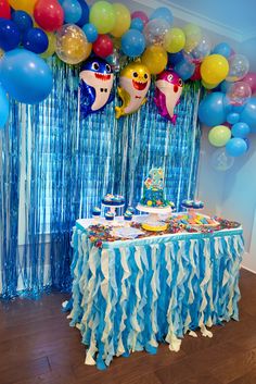 a birthday party with balloons and streamers on the wall, blue table cloths