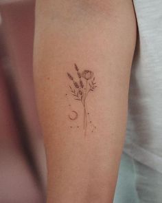 a small flower and moon tattoo on the arm