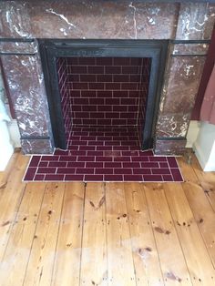 a brick fireplace in a room with wood flooring