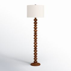 a wooden floor lamp with a white shade on the base and a light bulb in the middle