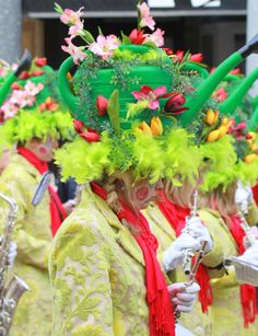 a group of people with hats and flowers on their heads are marching down the street