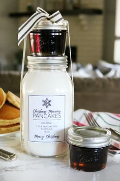 a jar of jam sitting on top of a table next to some pancakes and butter