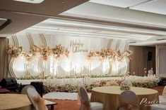 an elegant wedding setup with flowers and candles on the wall, decorated with gold ribbon