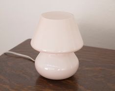 a white lamp sitting on top of a wooden table next to a phone charger