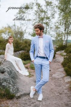 a man in a blue suit and bow tie walking down a path