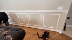 a black leather couch sitting on top of a hard wood floor next to a wall