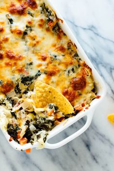 a casserole dish with cheese, spinach and tortilla chips in it