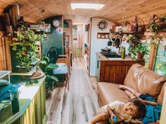 a woman laying on top of a couch in a living room next to a kitchen